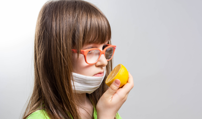 Menina tentando sentir o odor de uma laranja