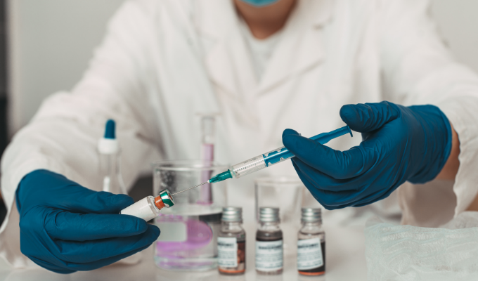 Nobel de Medicina 2023: um médico e pesquisador segurando um frasco de vacina à base de mRNA e injetando uma seringa