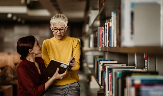Tipos de desinformação: uma bibliotecária ajudando uma aluna a encontrar um livro
