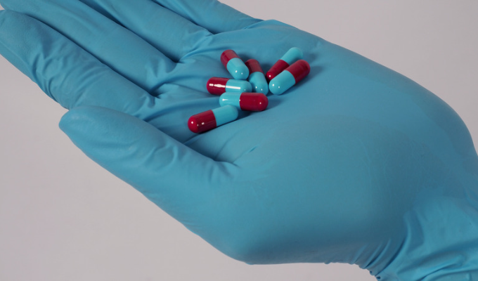 COVID-19: um médico com a mão protegida com luva segurando várias cápsulas de medicamento