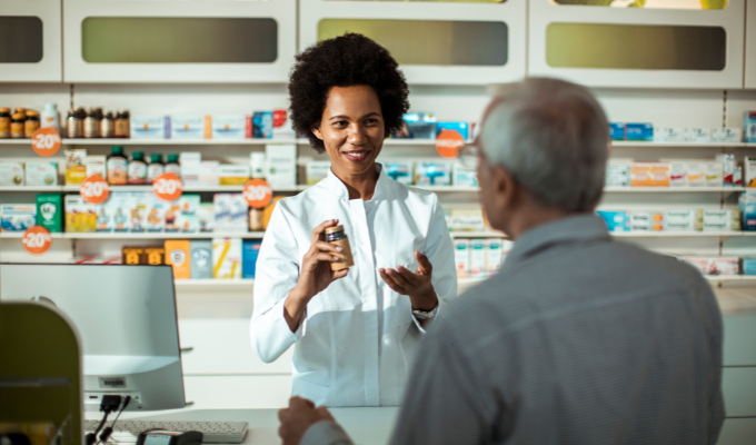 Farmácia: uma farmacêutica atendendo um cliente homem idoso em uma farmácia convencional
